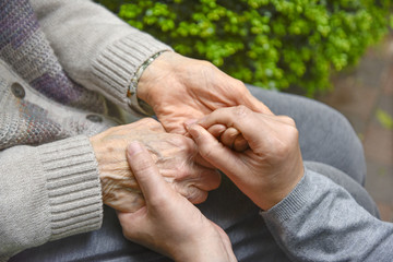 Close-up of an elderly person's hand being gently held by a younger caregiver, conveying care and support.